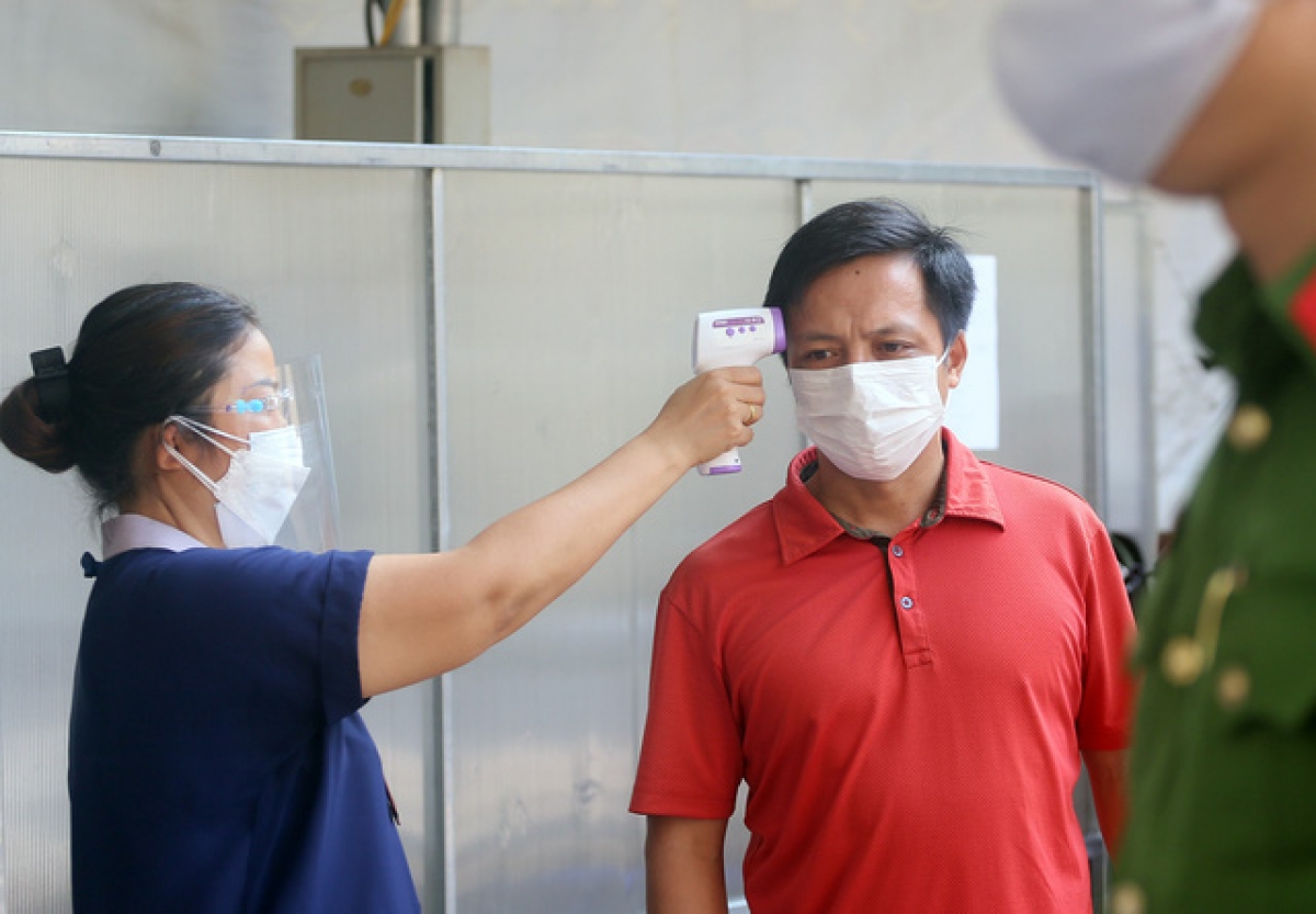 Người dân được đo thân nhiệt trước khi vào tiêm vaccine