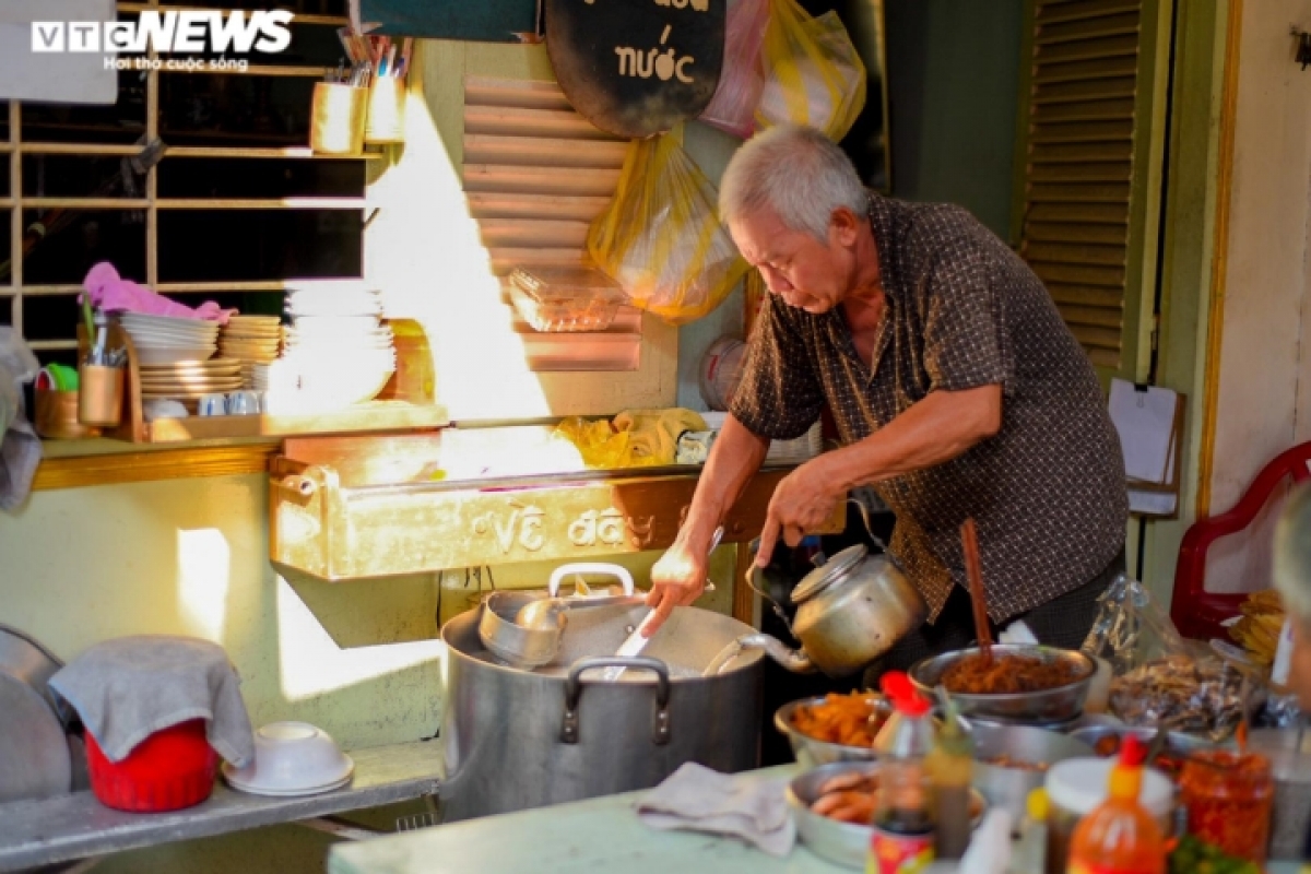 Ông Minh châm thêm nước sôi vào nồi cháo để giữ độ sánh vừa phải.