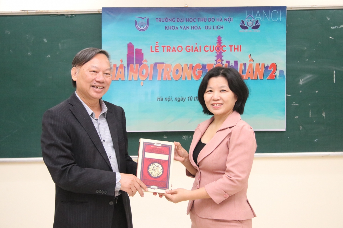 TS. Trịnh Ngọc Ánh, đại diện khoa Văn hóa Du lịch, Trường Đại học Thủ Đô Hà Nội nhận sách về Hà Nội từ GS.TS. NGND Nguyễn Quang Ngọc, góp thêm tư liệu giảng dạy bộ môn Hà Nội học.
