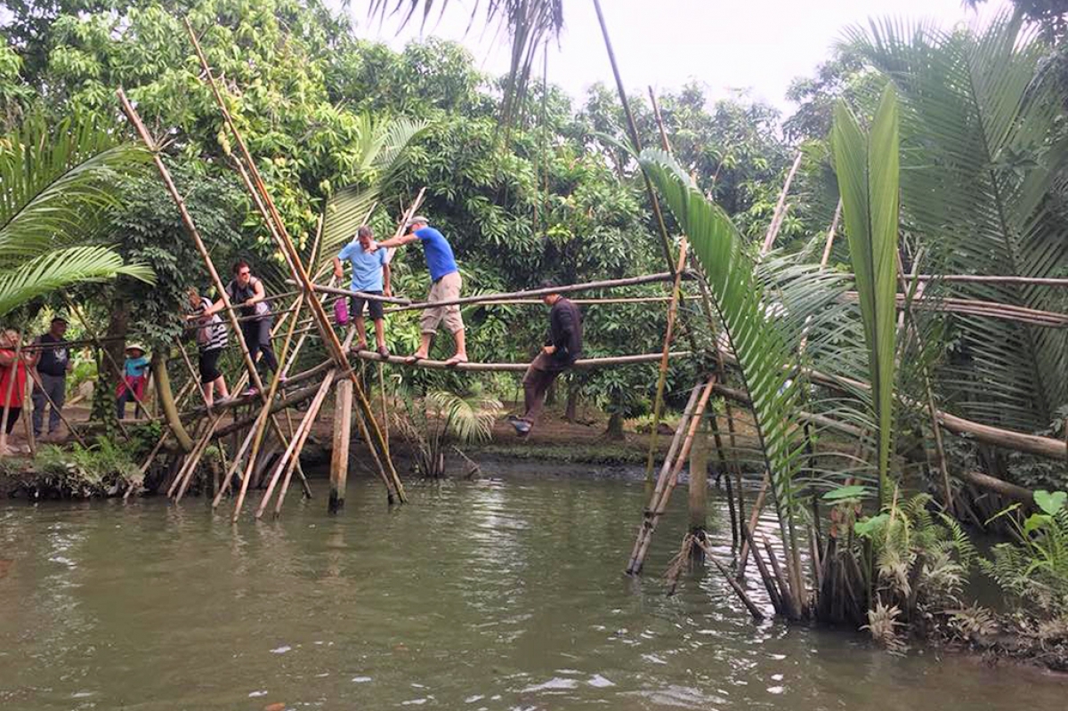 Du khách thích thú trải nghiệm đi cầu khỉ khi tham gia tour miệt vườn tại Cần Thơ