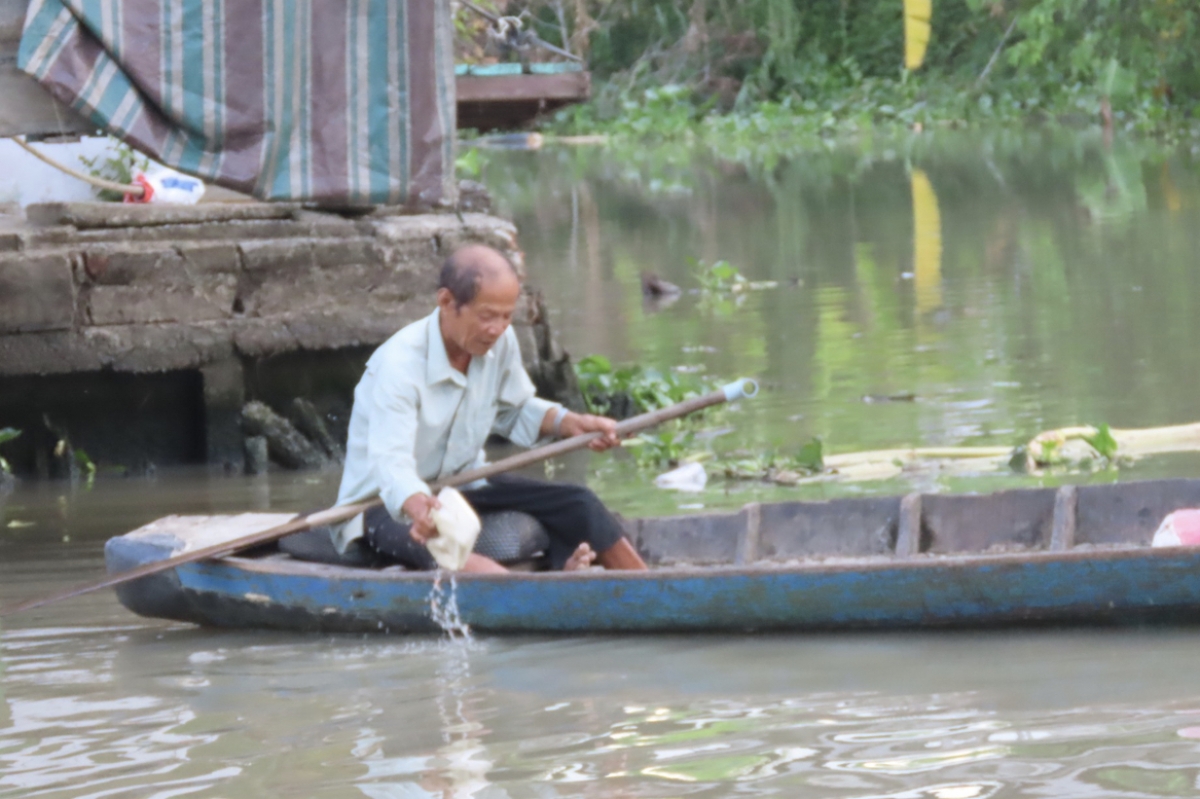 Ông Tuốt đang nhặt hộp cơm bị vứt xuống sông.