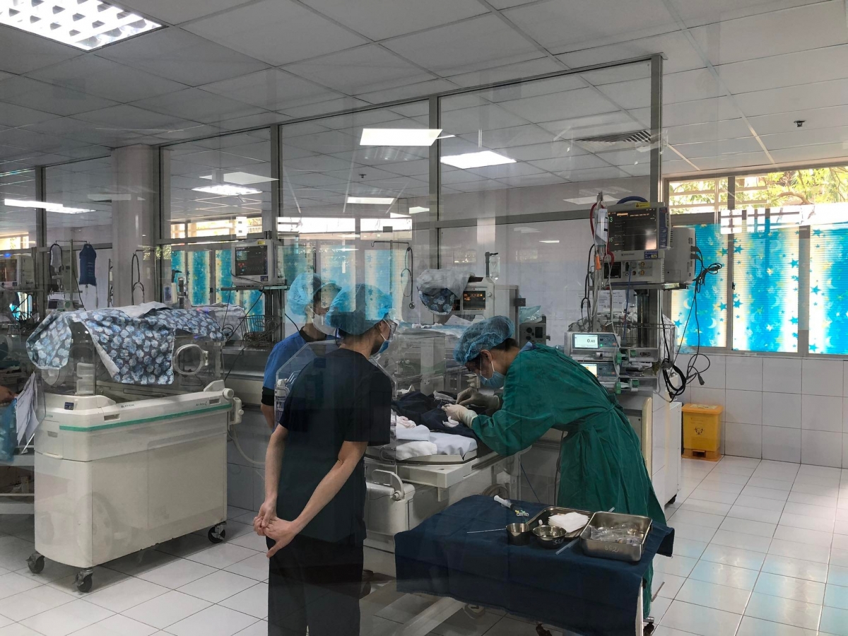 Các y bác sĩ làm tiểu phẫu cho một bé sinh non ngay tại lồng ấp
