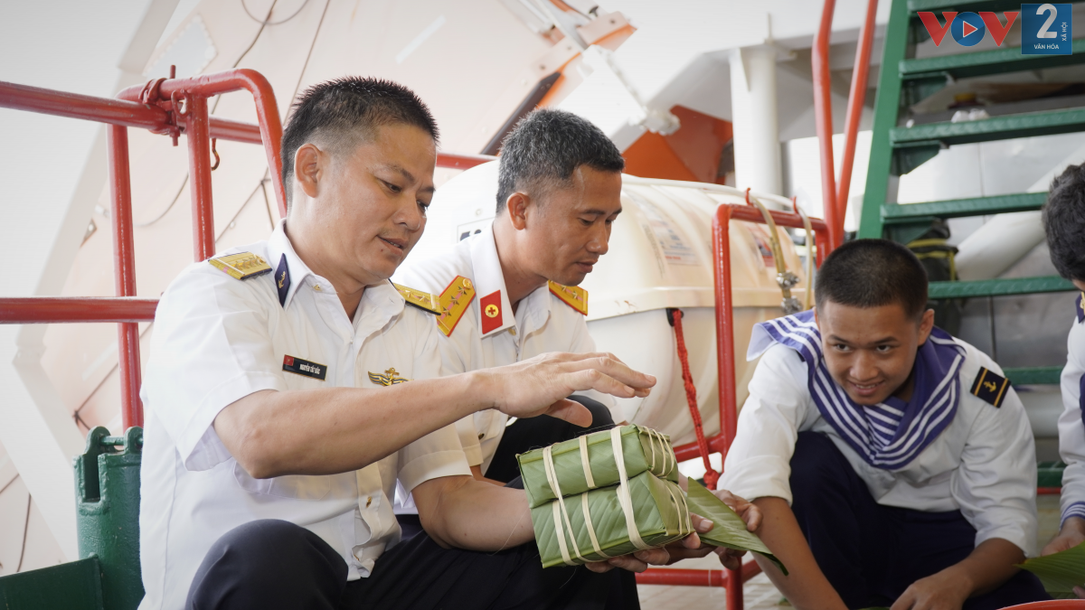Đại úy Nguyễn Tất Bắc, nhân viên vận hành hệ thống máy điện trên nhà giàn vui vẻ bên cặp bánh chưng vừa gói xong