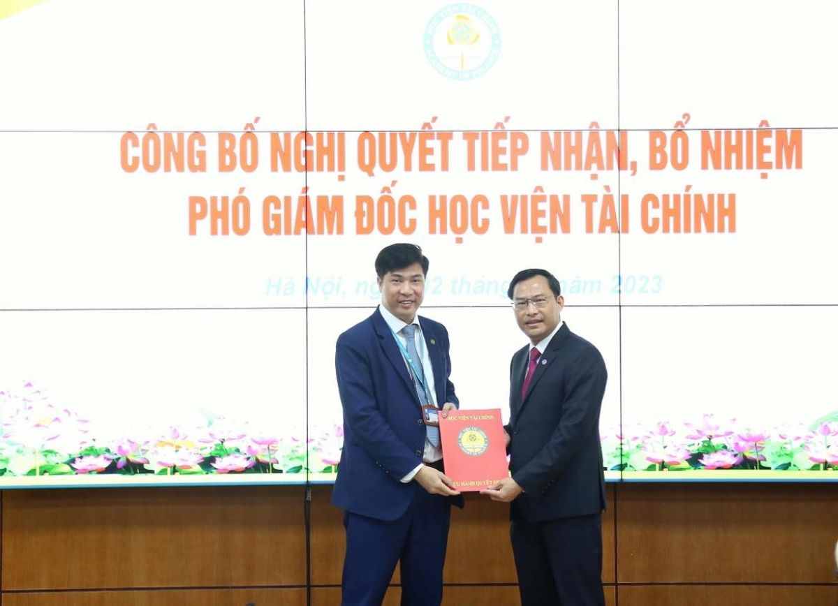 PGS.TS Nguyễn Đào Tùng - Chủ tịch Hội đồng trường Học viện Tài chính ( người đứng bên trái ) đã trao nghị quyết tiếp nhận, bổ nhiệm chức vụ Phó Giám đốc Học viện Tài chính cho TS. Nguyễn Văn Bình.