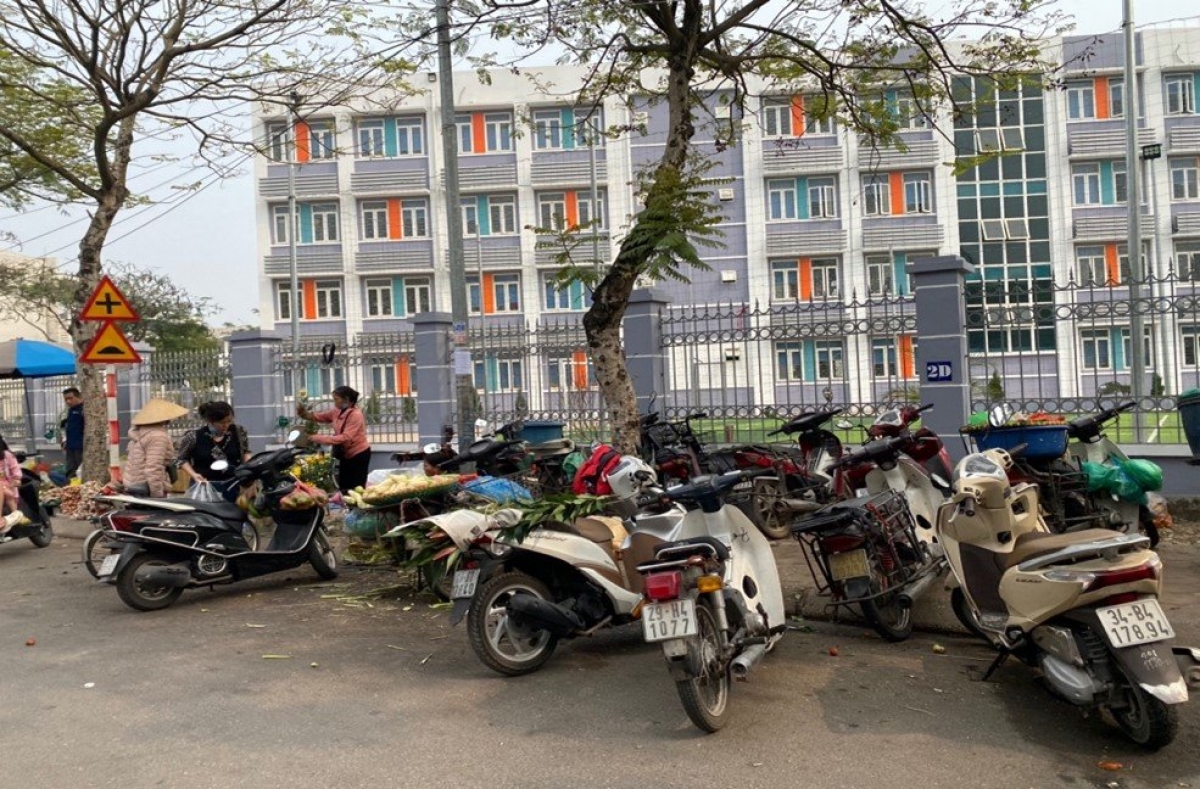 Đoạn vỉa hè sau khuôn viên trường biến thành khu vực để xe, hàng hóa, rác vung vãi trên mặt đường