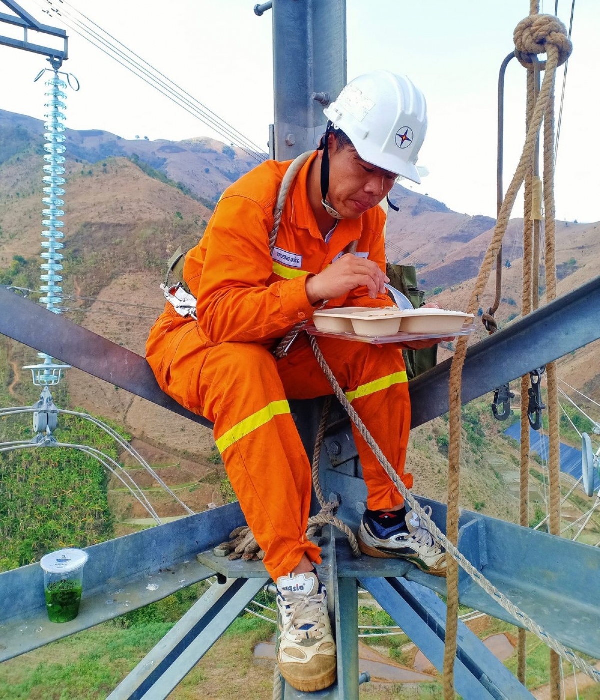 Để ưu tiên tối đa thời gian cho công việc, những bữa ăn vội ngay trên cột điện, giữa lưng chừng trời cao hàng chục mét không còn xa lạ với những người “lính” truyền tải điện (Ảnh KT)