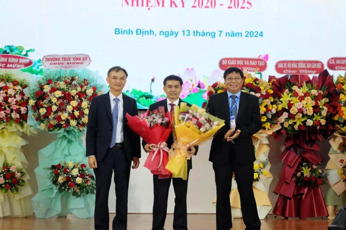 Ông Nguyễn Viết Lộc (bìa trái) - Vụ trưởng Vụ tổ chức cán bộ (Bộ GD&ĐT) tặng hoa chúc mừng tân hiệu trưởng PGS.TS Đoàn Đức Tùng.