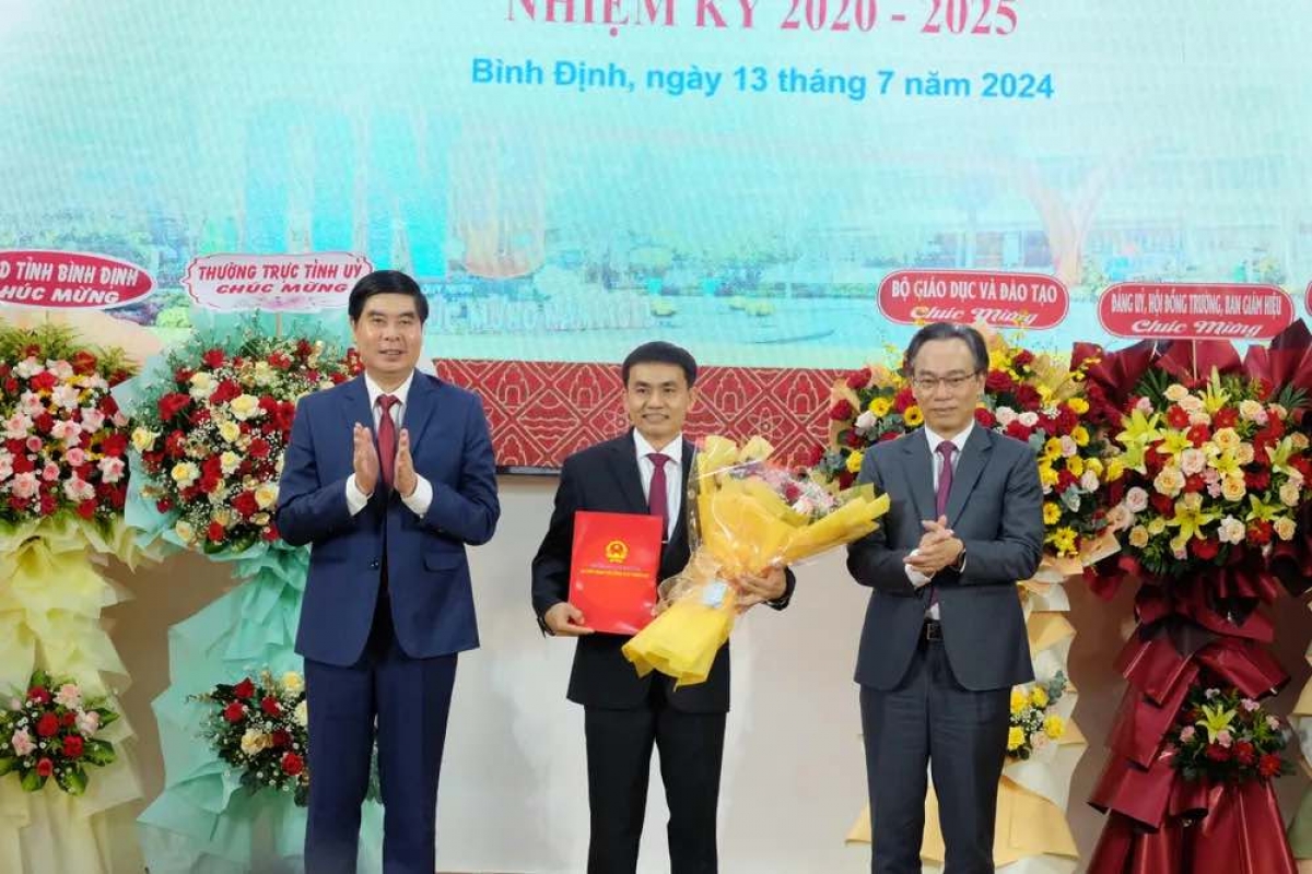 Thứ trưởng Bộ GD&ĐT Hoàng Minh Sơn (ngoài cùng bên phải) trao quyết định và ông Lâm Hải Giang - Phó Chủ tịch UBND tỉnh Bình Định tặng hoa chúc mừng PGS.TS Đoàn Đức Tùng.