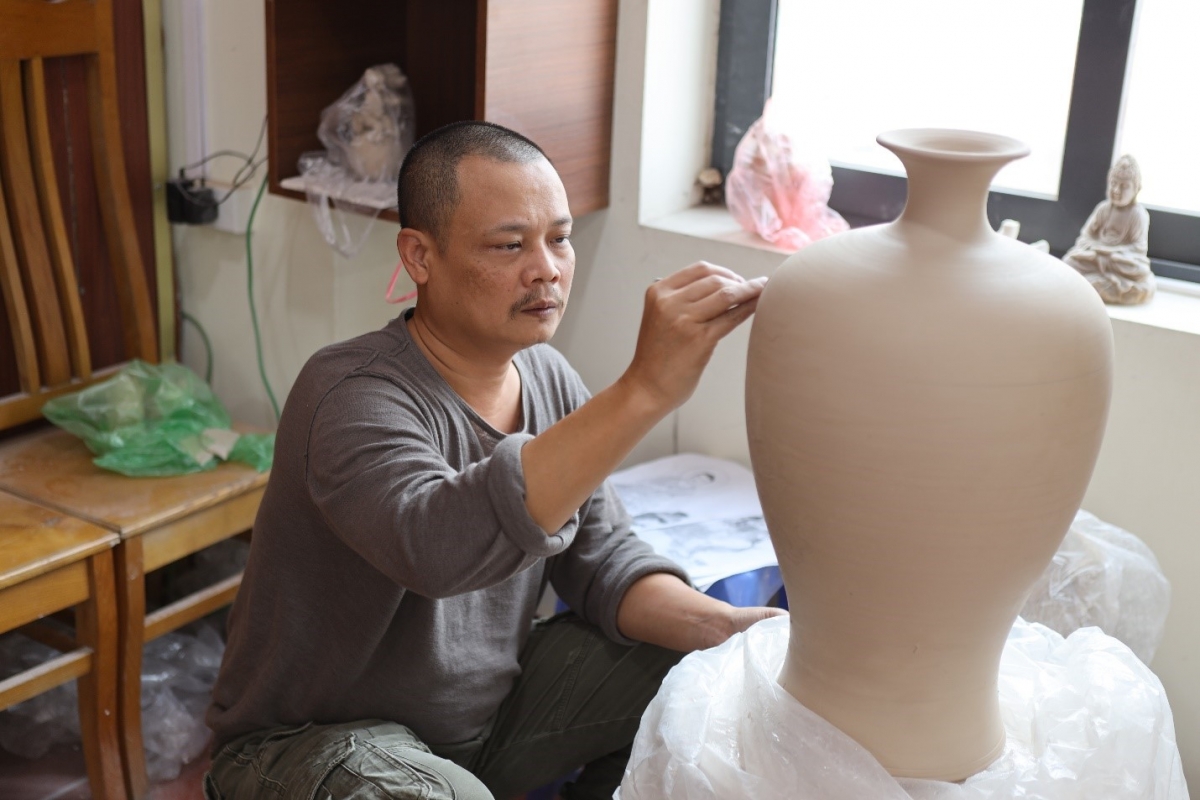 Nghệ nhân Trần Doãn Tuyền tỉ mỉ tạo khắc các họa tiết trên bình gốm. Ảnh: Hồng Ngọc