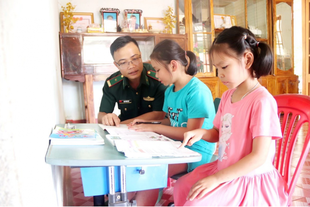 Thiếu tá Cao Thanh Lực, Đội trưởng Đội VĐQC hướng dẫn hai cháu con nuôi Đồn Biên phòng học tập